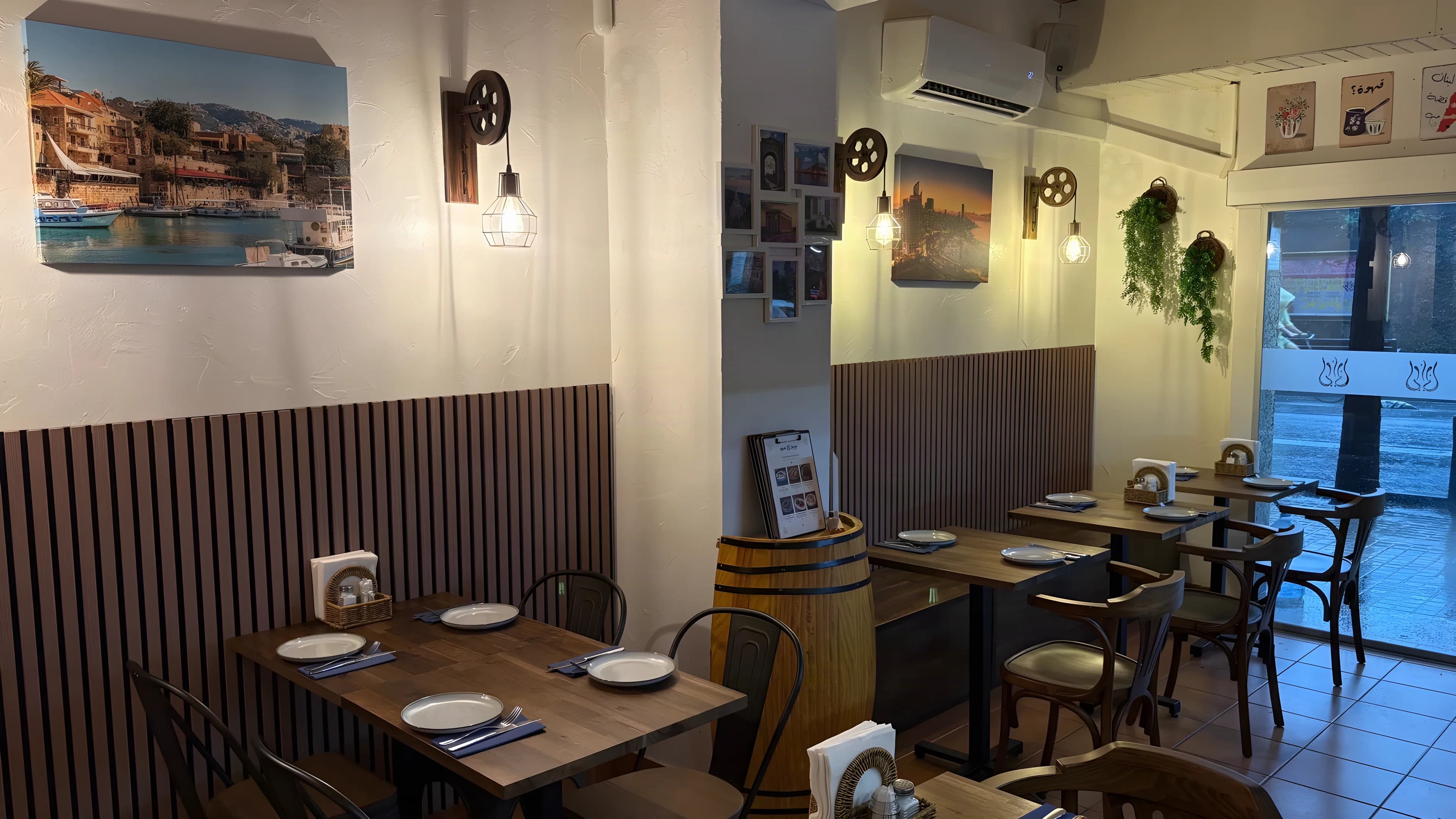 La sala de Layali Beirut, con mesas y sillas de madera, lámparas colgantes y fotografías de Beirut.
